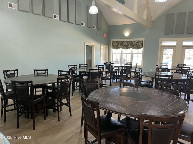 dining area featuring high vaulted ceiling and light wood finished floors
