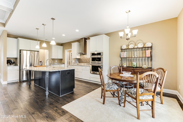 kitchen with appliances with stainless steel finishes, wall chimney range hood, dark wood finished floors, tasteful backsplash, and recessed lighting