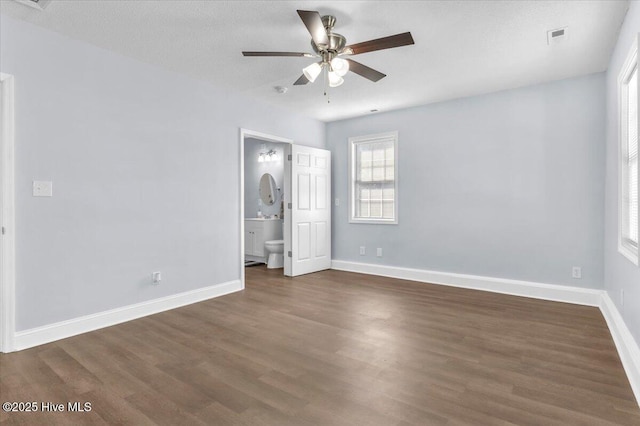 235 Zachary Ln, Hubert, NC 28539 - unfurnished bedroom with dark wood-type flooring, baseboards, ensuite bathroom, and ceiling fan