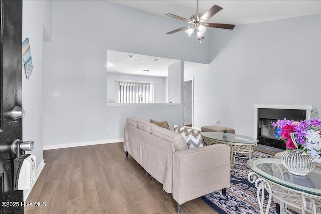 235 Zachary Ln, Hubert, NC 28539 - living area featuring wood finished floors, a ceiling fan, a fireplace with flush hearth, baseboards, and a towering ceiling