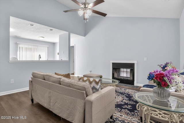 235 Zachary Ln, Hubert, NC 28539 - living room featuring a ceiling fan, a glass covered fireplace, dark wood-type flooring, baseboards, and a high ceiling