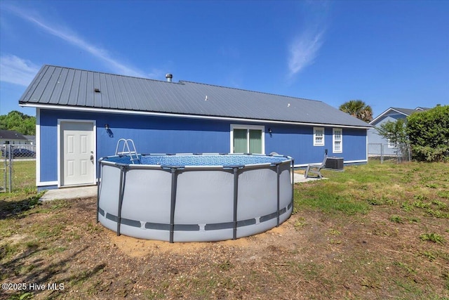 235 Zachary Ln, Hubert, NC 28539 - rear view of property with central air condition unit, fence, an outdoor pool, and metal roof