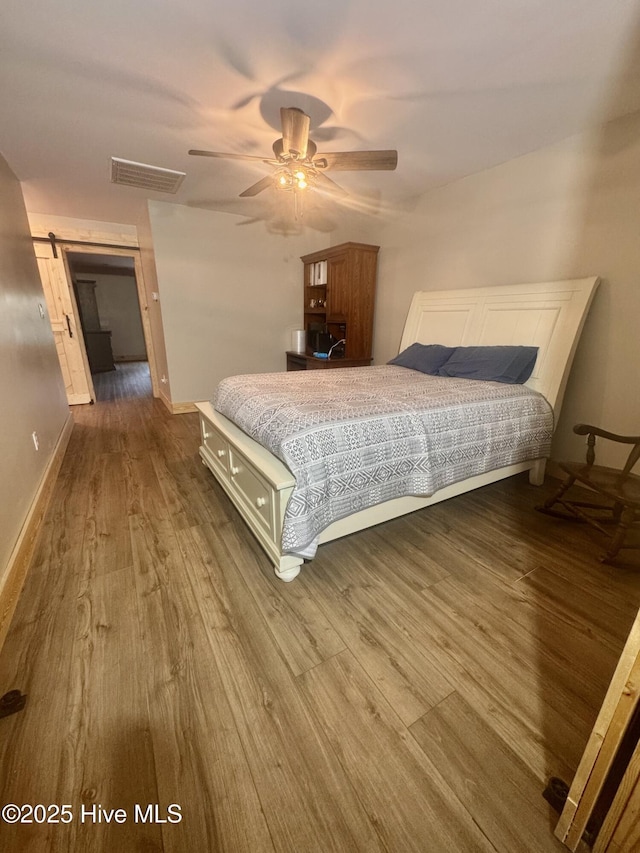 200 Wintergreen Patch Ln, Burnsville, NC 28714 - bedroom with dark wood-type flooring, a barn door, a ceiling fan, and baseboards