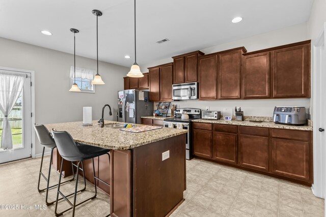 203 Holmes Point Ct, Jacksonville, NC 28546 - kitchen featuring appliances with stainless steel finishes, a sink, a breakfast bar area, a kitchen island with sink, and light stone counters