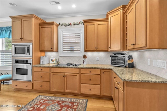 kitchen with appliances with stainless steel finishes, light wood-type flooring, ornamental molding, light stone countertops, and tasteful backsplash