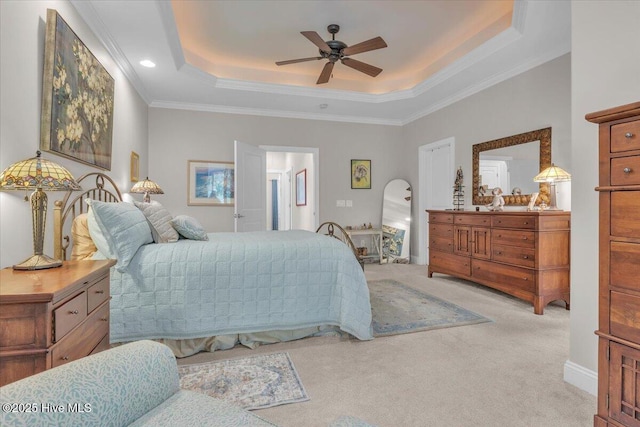bedroom featuring carpet flooring, a tray ceiling, crown molding, and a ceiling fan