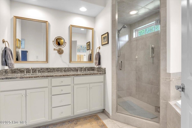 bathroom featuring a shower stall, double vanity, and tile patterned flooring
