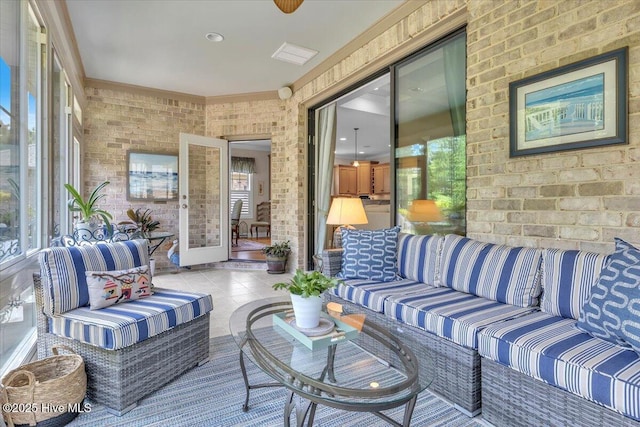 sunroom with plenty of natural light, brick wall, and tile patterned floors