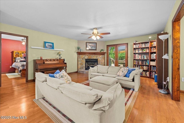 476 Paige Riddick Rd, Gates, NC 27937 - living room featuring a ceiling fan, a stone fireplace, light wood-type flooring, and baseboards