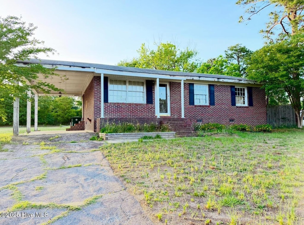 ranch-style home featuring brick siding, asphalt driveway, an attached carport, and fence
