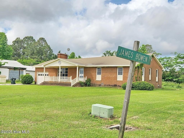view of front of house featuring covered porch, an attached garage, a front yard, brick siding, and a chimney