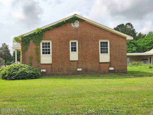 view of side of property featuring brick siding, a lawn, and crawl space
