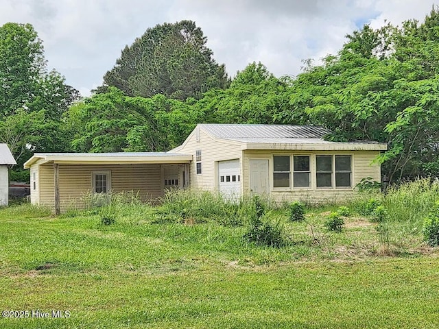 view of front of property featuring a garage, a front lawn, and metal roof