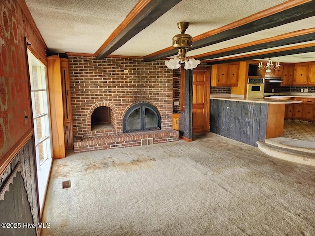 unfurnished living room with a fireplace, a textured ceiling, carpet flooring, beamed ceiling, and ceiling fan