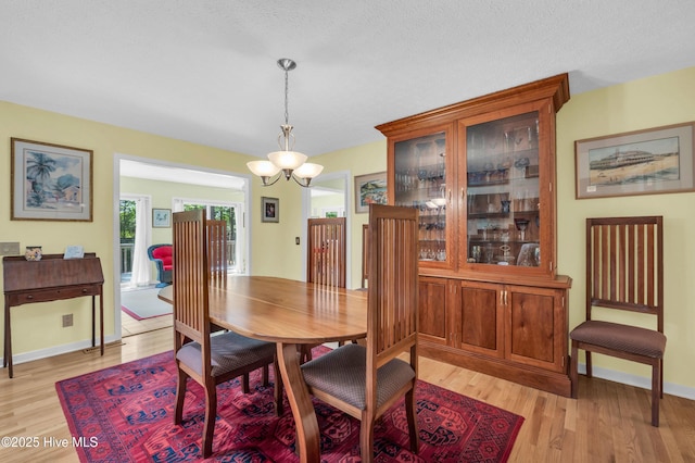 dining area with light wood finished floors, a chandelier, and baseboards