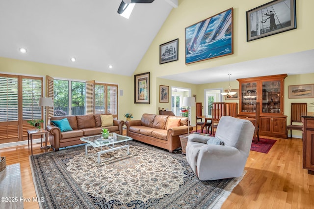 living area with high vaulted ceiling, light wood-type flooring, recessed lighting, and a chandelier
