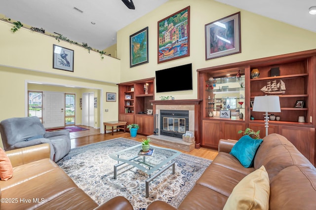 living area with light wood-style floors, a glass covered fireplace, and a high ceiling