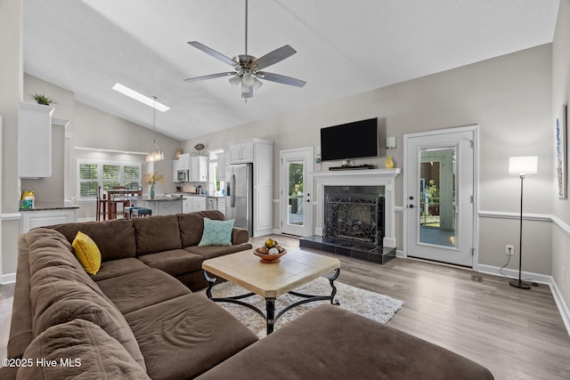 306 Channel Run Dr, New Bern, NC 28562 - living room featuring lofted ceiling, a tiled fireplace, ceiling fan, light wood-style flooring, and baseboards