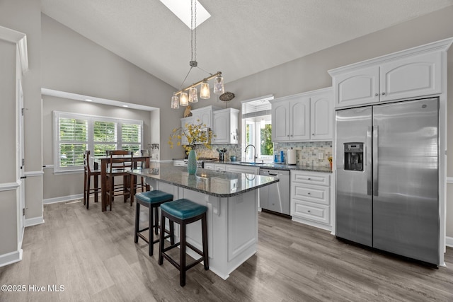 306 Channel Run Dr, New Bern, NC 28562 - kitchen with appliances with stainless steel finishes, white cabinets, wood finished floors, backsplash, and lofted ceiling