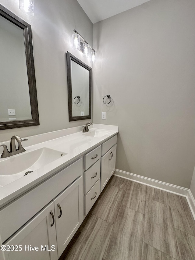 bathroom with double vanity, baseboards, and wood finished floors