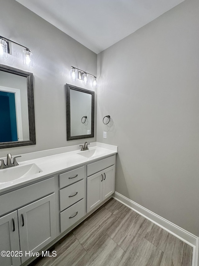bathroom featuring double vanity, baseboards, and wood finished floors