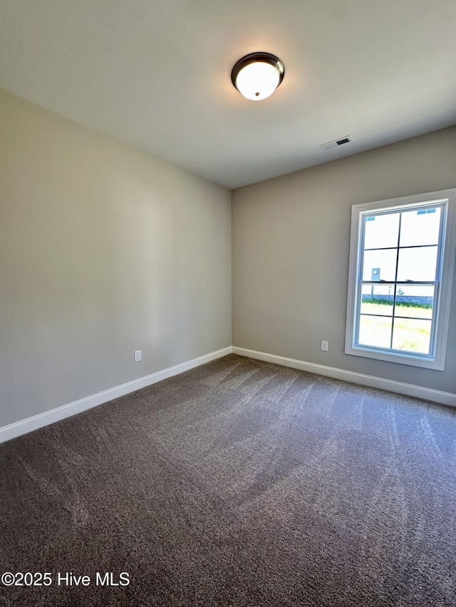 empty room featuring baseboards and dark carpet