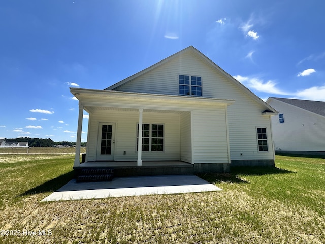 rear view of property featuring covered porch and a yard