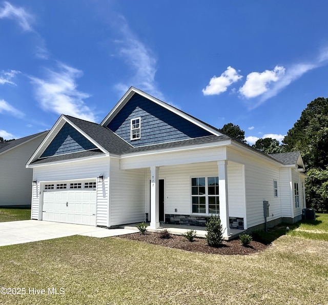 view of front of house with covered porch, a garage, driveway, a front yard, and roof with shingles