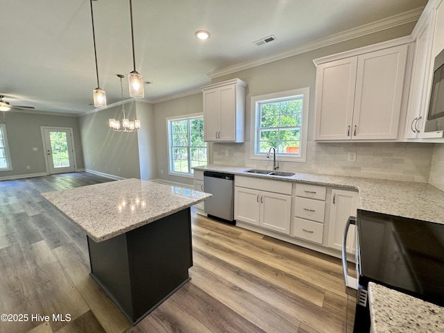 kitchen featuring dishwasher, a sink, range, crown molding, and plenty of natural light