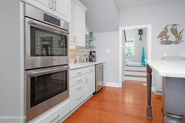 555 Dawson Creek Dr, Arapahoe, NC 28510 - kitchen featuring double oven, beverage cooler, a sink, tasteful backsplash, and light wood finished floors