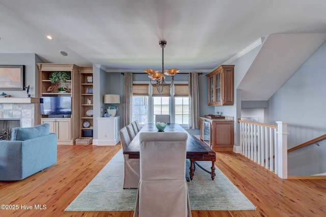 dining area with a chandelier, light wood-style flooring, a fireplace, wine cooler, and lofted ceiling