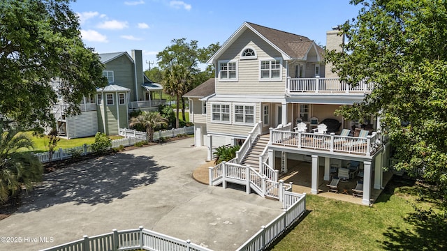 back of house with concrete driveway, stairway, a patio, and a balcony