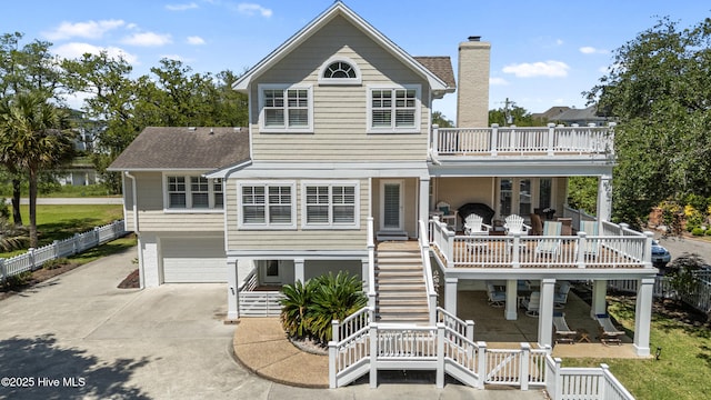back of property with stairs, a chimney, concrete driveway, a garage, and fence