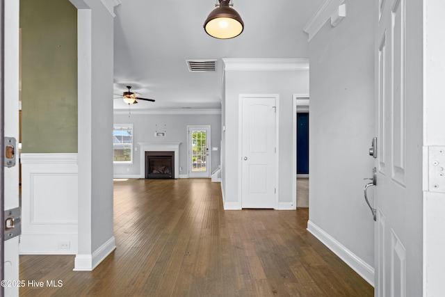 foyer entrance with ceiling fan, dark wood finished floors, ornamental molding, baseboards, and a fireplace