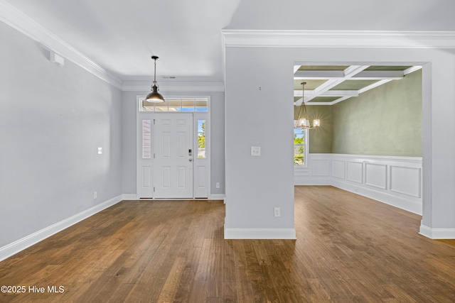 entrance foyer with crown molding, wood finished floors, a chandelier, a wainscoted wall, and coffered ceiling