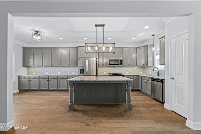 kitchen featuring appliances with stainless steel finishes, gray cabinetry, ornamental molding, backsplash, and light stone counters