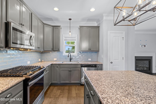 kitchen with stainless steel appliances, gray cabinetry, a sink, dark wood finished floors, and crown molding