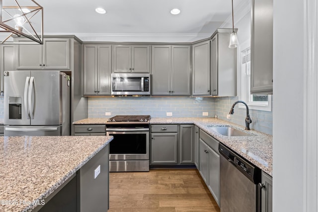 kitchen with appliances with stainless steel finishes, gray cabinets, a sink, wood finished floors, and recessed lighting