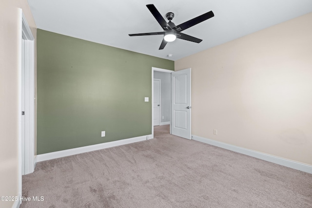 carpeted spare room featuring a ceiling fan and baseboards