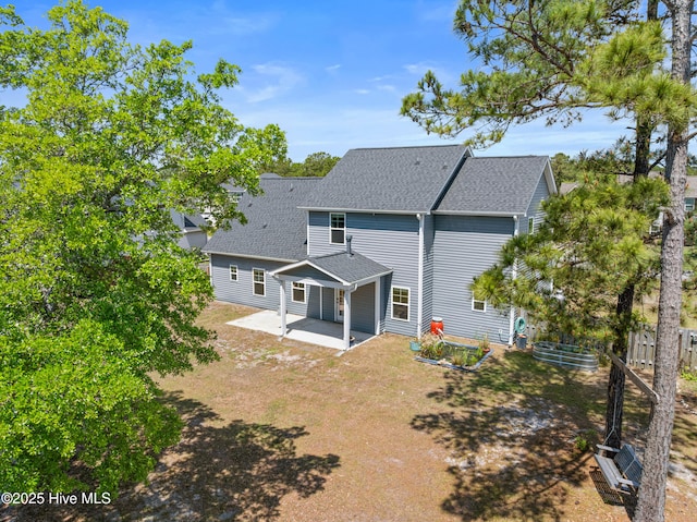 back of house featuring a patio and roof with shingles