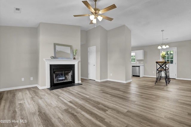 117 Clint Mills Rd, Maysville, NC 28555 - unfurnished living room with wood finished floors, a ceiling fan, a fireplace with flush hearth, a chandelier, and vaulted ceiling