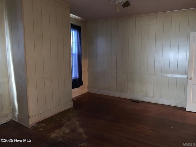 empty room featuring wood finished floors, a ceiling fan, and wood walls