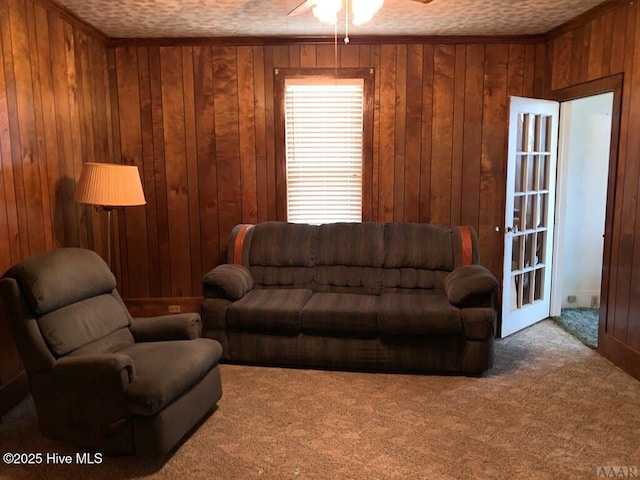 living area with carpet floors, ceiling fan, and wooden walls