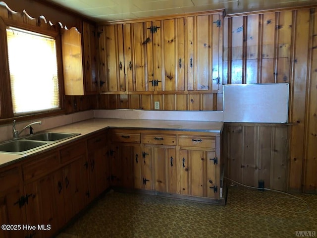 kitchen with a sink, brown cabinets, dark floors, and light countertops