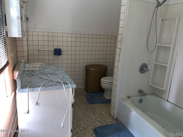 bathroom with tile walls, toilet, tub / shower combination, and tile patterned floors