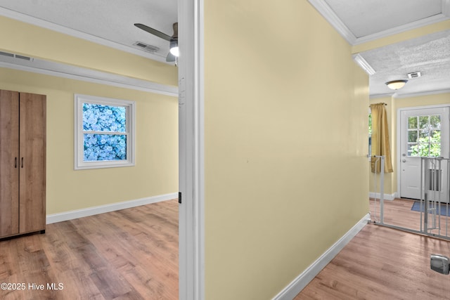 hall with crown molding, baseboards, wood finished floors, and a textured ceiling
