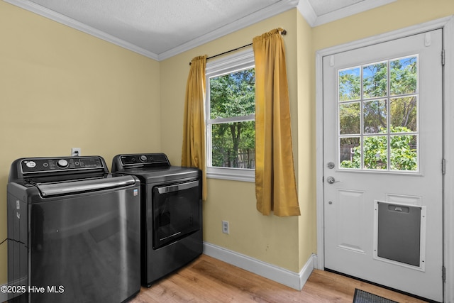 laundry area featuring ornamental molding, independent washer and dryer, baseboards, and light wood finished floors