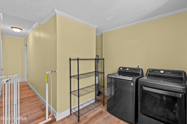 washroom with crown molding, washer and clothes dryer, light wood-style floors, baseboards, and a textured ceiling