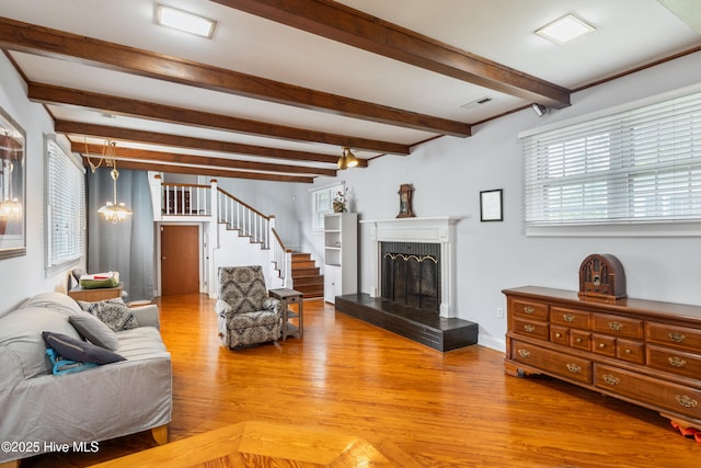 1306 W Church St, Elizabeth City, NC 27909 - living area with light wood-style flooring, beamed ceiling, stairs, and a fireplace with raised hearth
