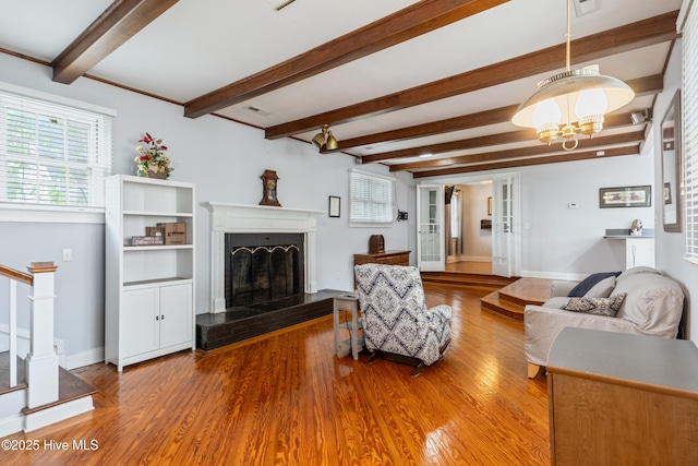 1306 W Church St, Elizabeth City, NC 27909 - living area featuring a fireplace with raised hearth, wood finished floors, beam ceiling, and plenty of natural light